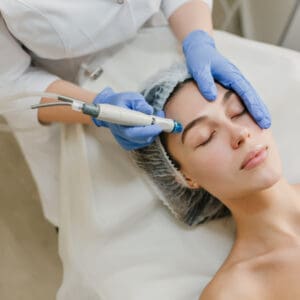 View from above rejuvenation of beautiful woman enjoying cosmetology procedures in beauty salon. Dermatology, hands in blue glows, healthcare, therapy, botox